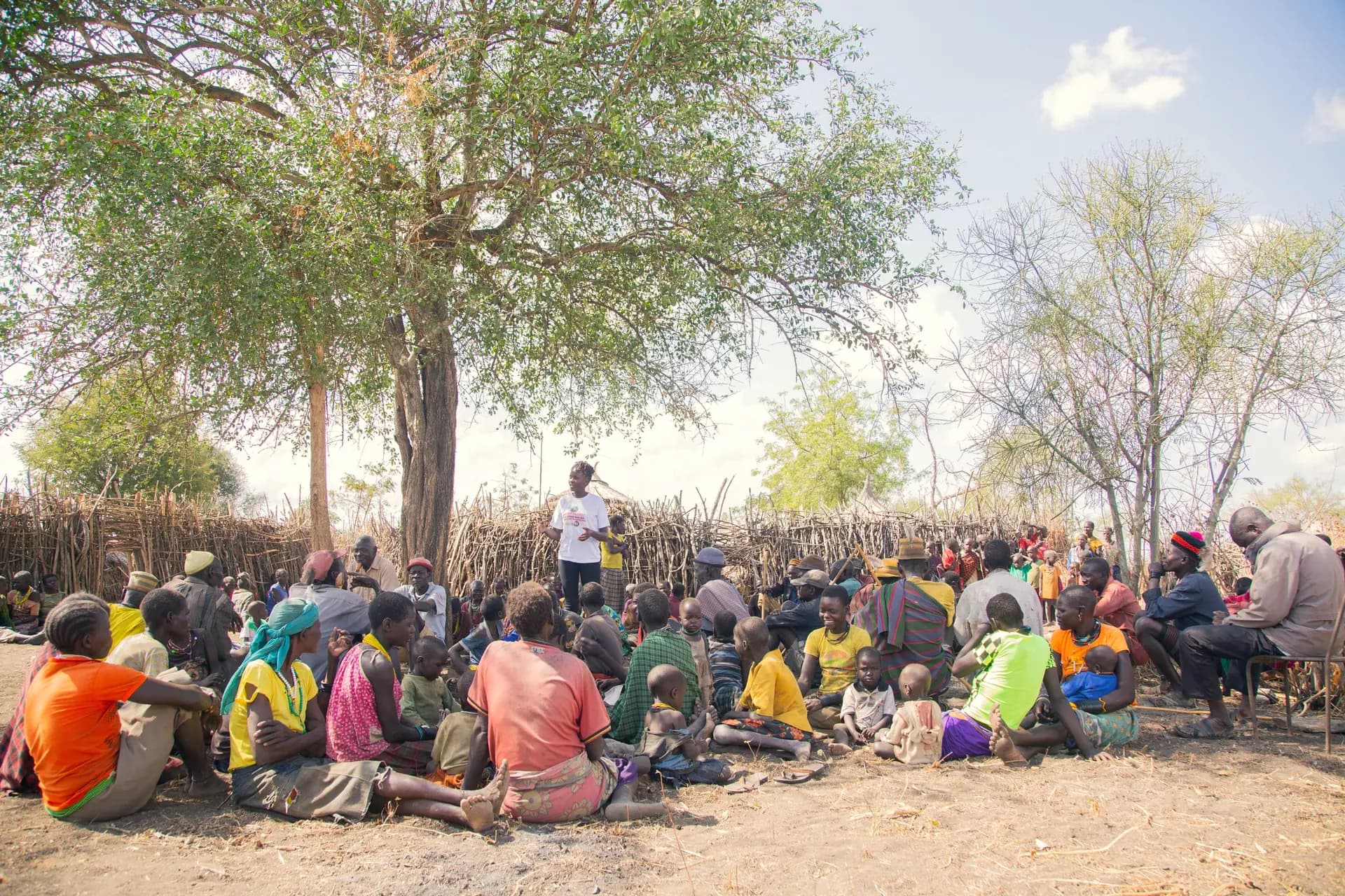 Neighbors sit under a tree for a community meeting.