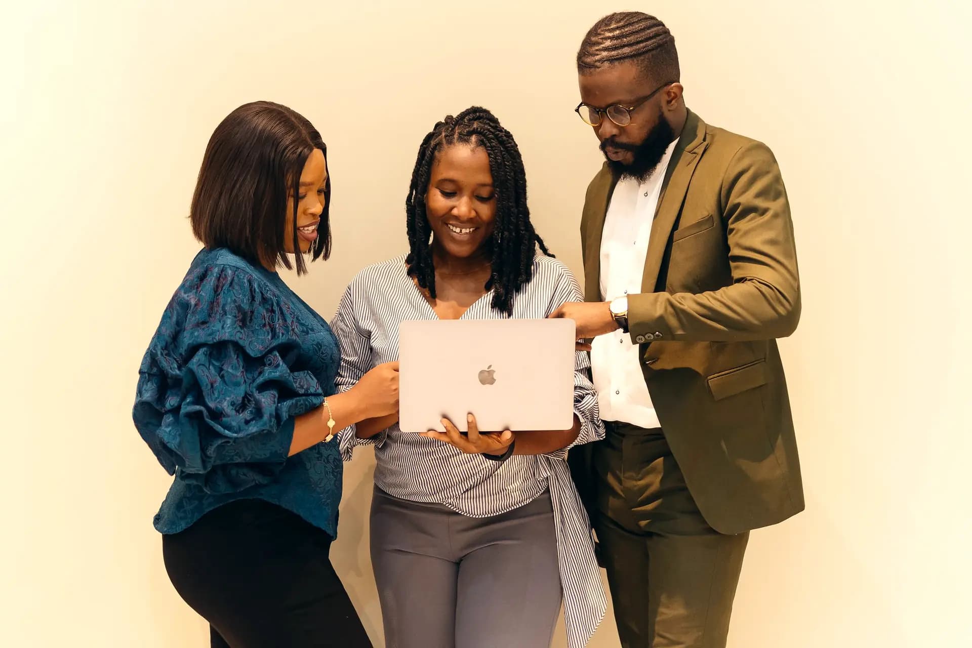 Three colleagues check a laptop together.